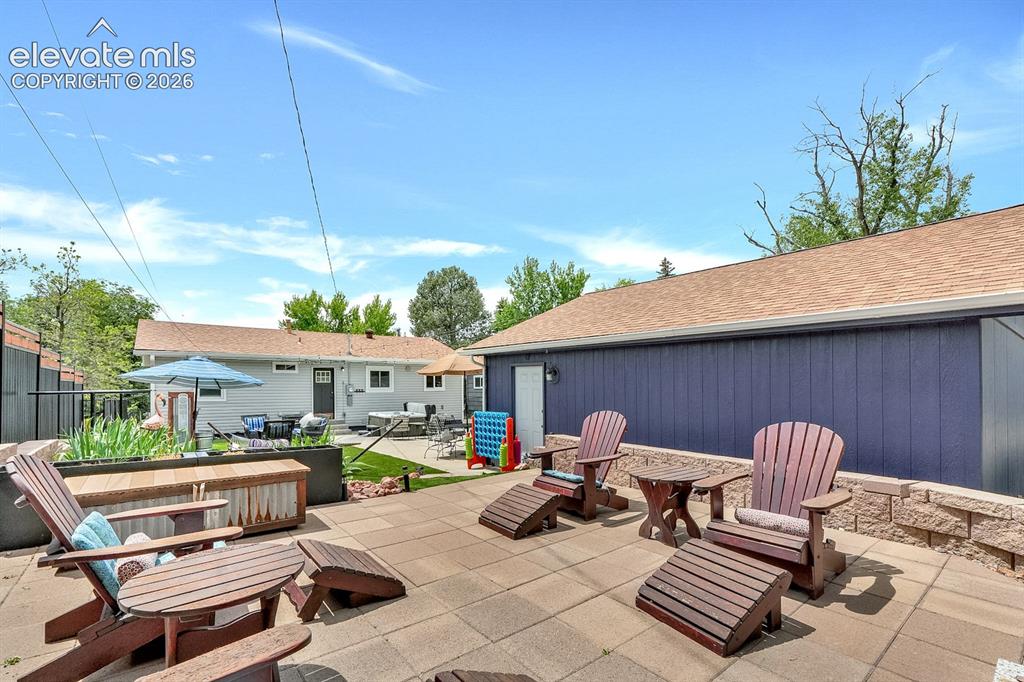 Image 26 of 33: Expansive patio featuring large format pavers, a low retaining wall, and a 