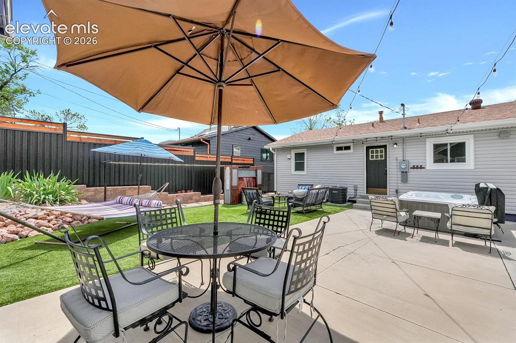 Image 27 of 33: Expansive backyard patio featuring concrete surfacing, artificial turf, a p