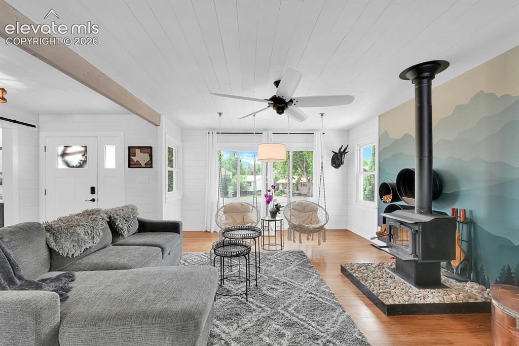 Image 3 of 33: Expansive living area featuring wood-finish flooring, a wood-burning stove 