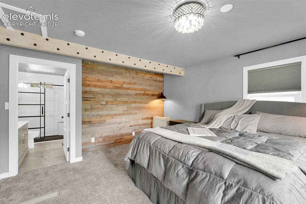 Image 4 of 33: Bedroom featuring wood-panel accent wall, recessed lighting, and a crystal 