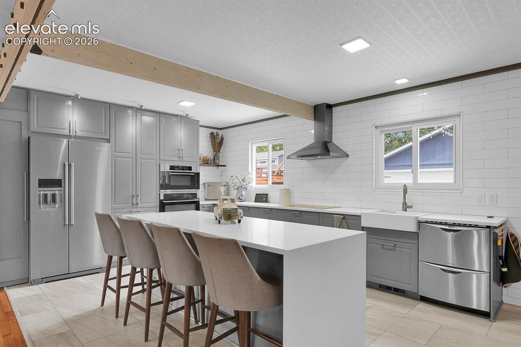 Image 8 of 33: Modern kitchen featuring a large central island with seating, stainless ste