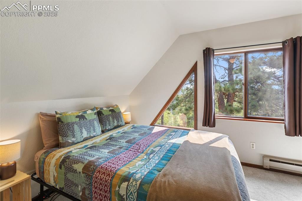 Image 24 of 45: Carpeted Upper Level bedroom with lofted ceiling, multiple windows, and a b