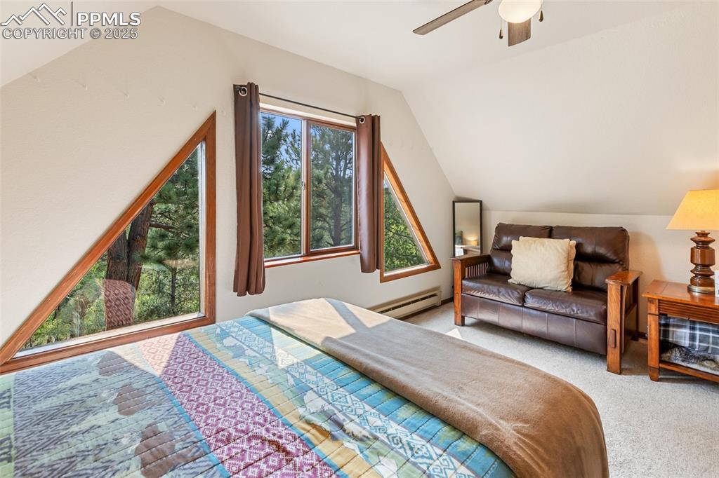 Image 25 of 45: upper level Bedroom with carpet, vaulted ceiling, a baseboard heating unit,