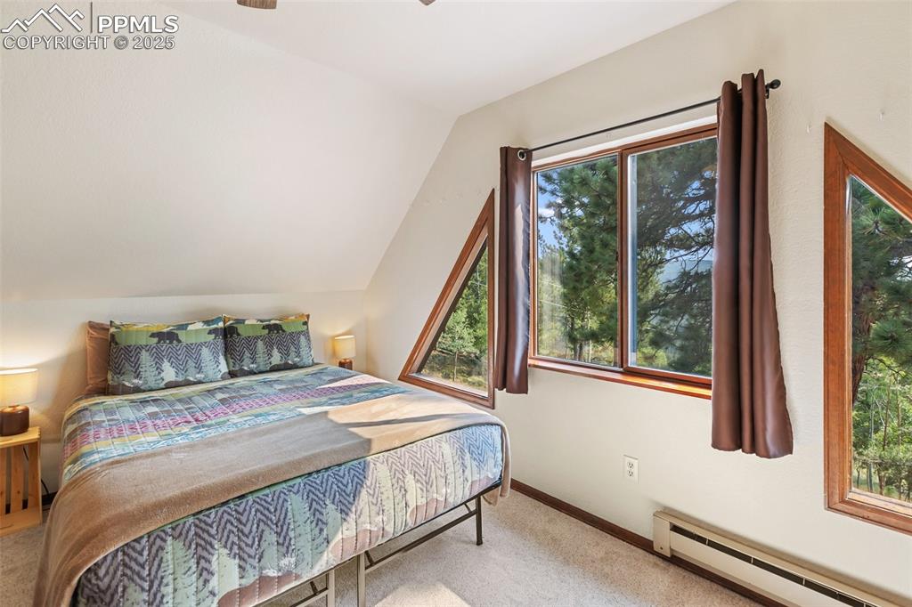 Image 27 of 45: Upper Level Bedroom with lofted ceiling, baseboard heating, light colored c