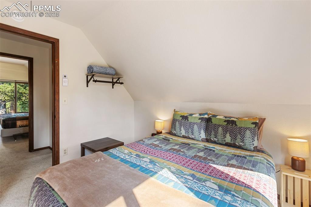 Image 28 of 45: Carpeted upper level bedroom with vaulted ceiling