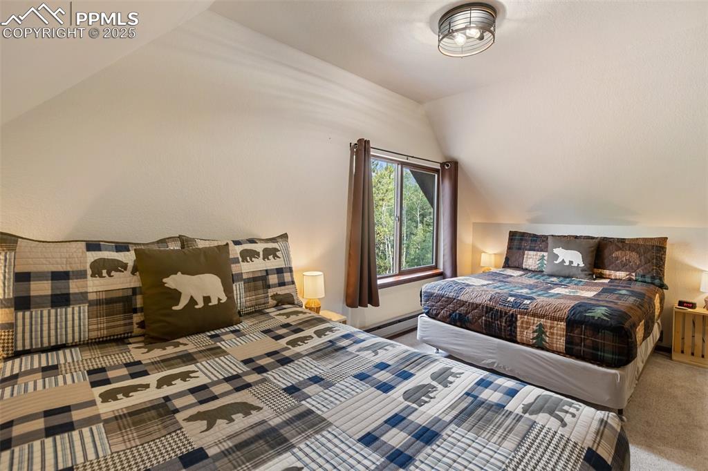 Image 31 of 45: Upper level Carpeted bedroom featuring lofted ceiling and a baseboard radia