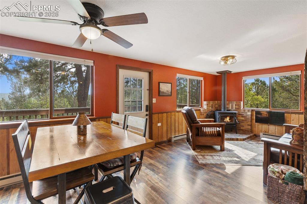 Image 7 of 45: Dining space with wainscoting, a wood stove, hardwood / wood-style flooring