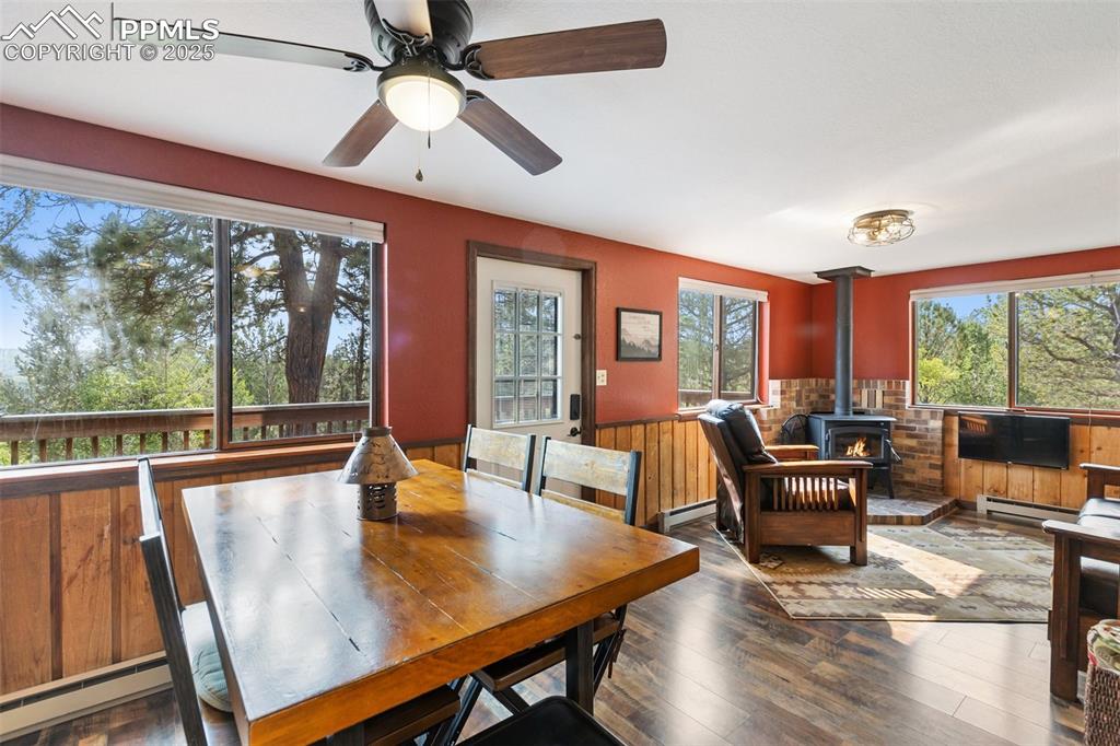 Image 9 of 45: Dining area with a wood stove, wainscoting, wood-type flooring, wood walls,