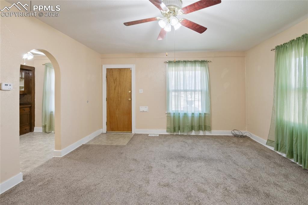 Image 14 of 28: Unfurnished room with arched walkways, carpet floors, and a ceiling fan