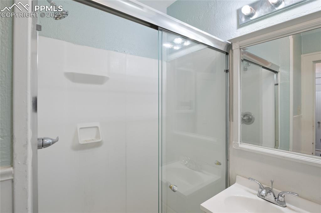 Image 22 of 28: Full bath with a shower, tile walls, and vanity