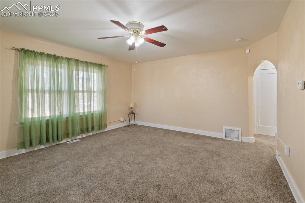Image 9 of 28: Carpeted empty room with arched walkways and a ceiling fan