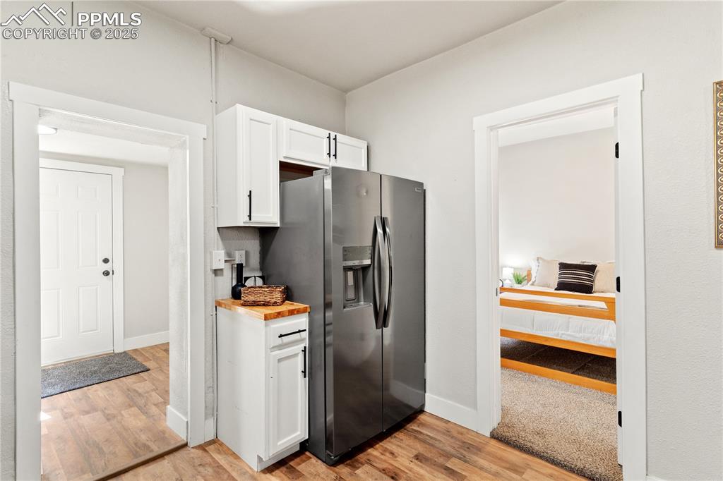 Image 5 of 13: Kitchen with stainless steel fridge, white cabinets, and light wood-style f