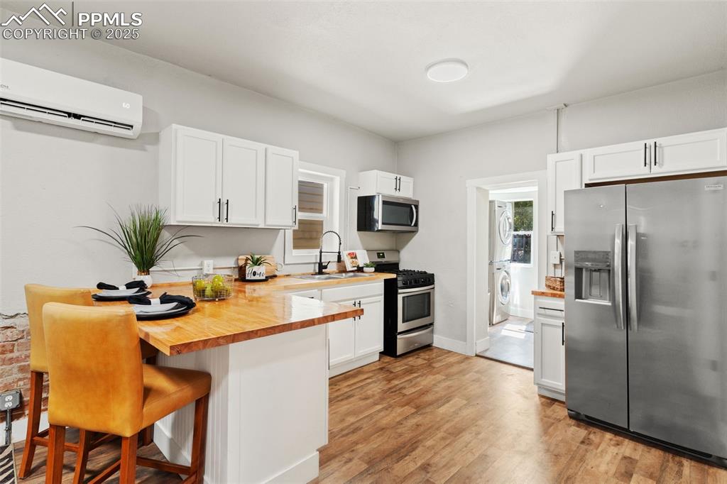 Image 8 of 13: Kitchen with stainless steel appliances, stacked washer / drying machine, a