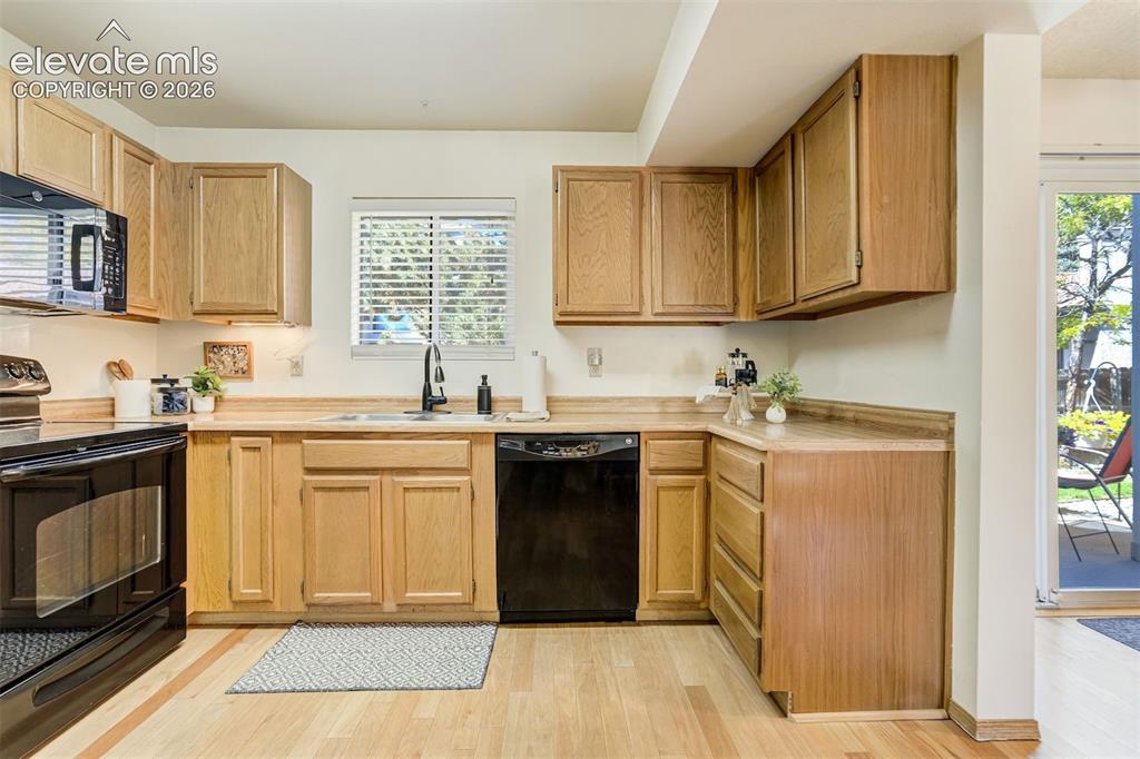 Image 12 of 50: Kitchen featuring wood-finish flooring, natural wood cabinetry, a black bui