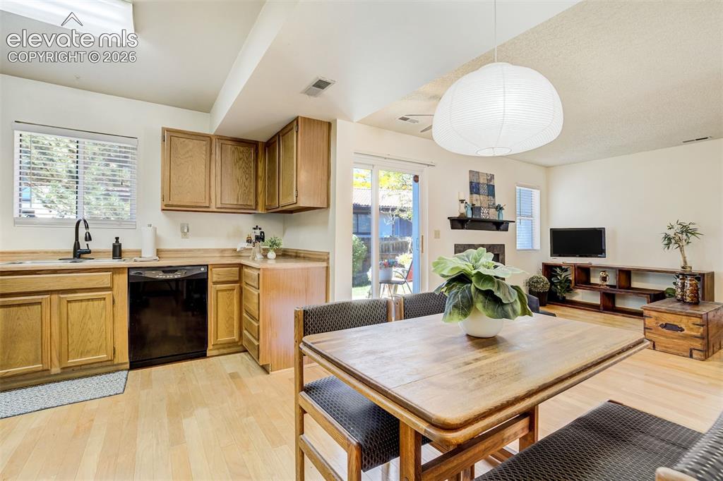 Image 13 of 50: Kitchen and dining area featuring wood-finish flooring, wood cabinetry, a s