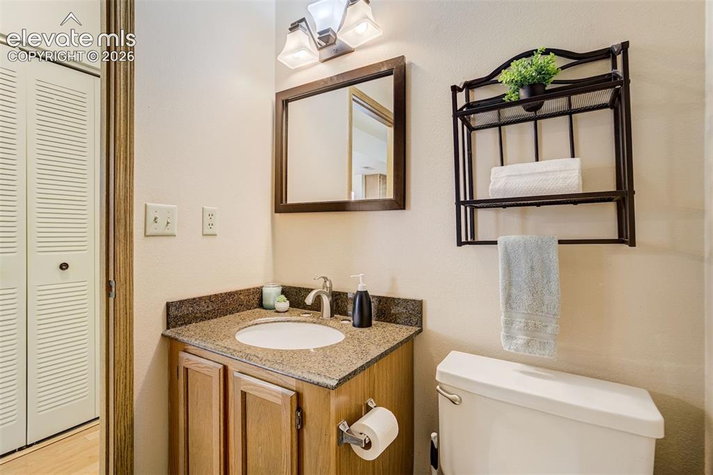 Image 16 of 50: Vanity with a granite countertop and an undermount sink, framed mirror, and