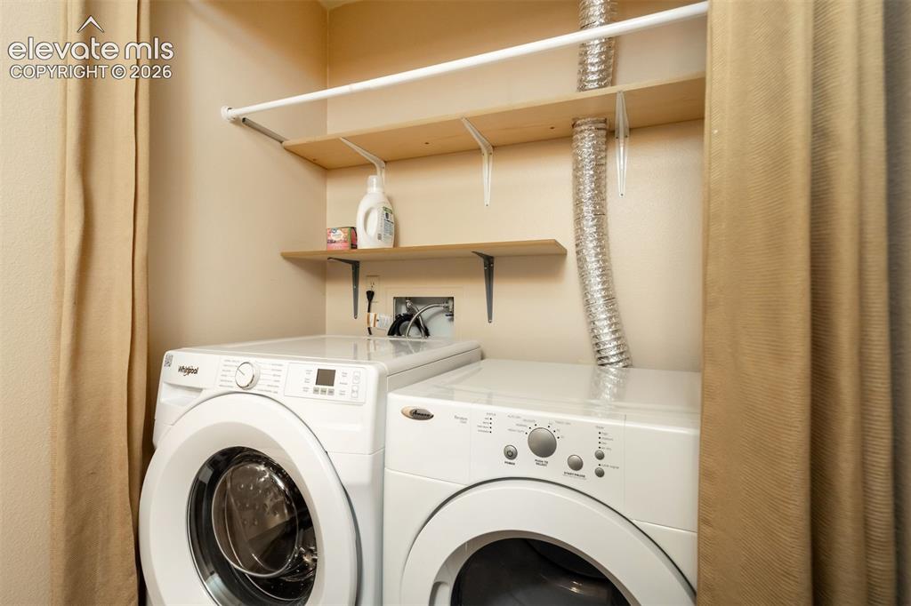 Image 17 of 50: Stacked laundry appliances with integrated shelving and a clothes hanging r