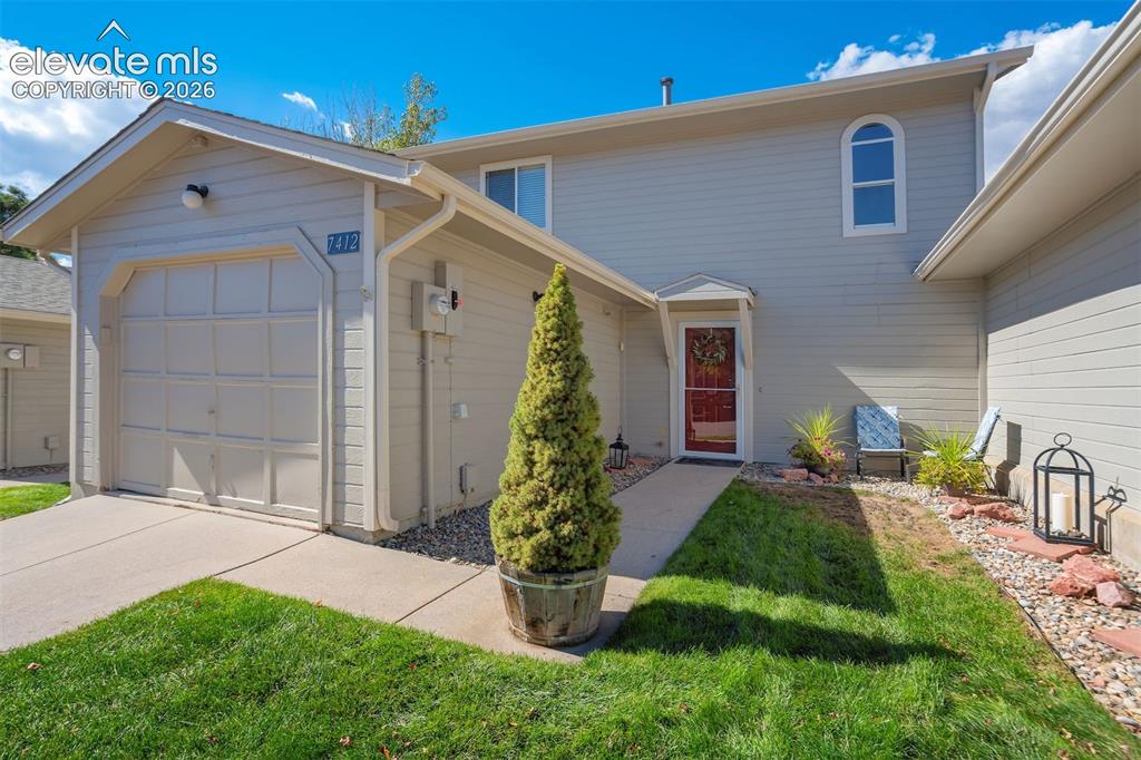 Image 2 of 50: Light-colored siding exterior with an attached garage, a walkway, and a red