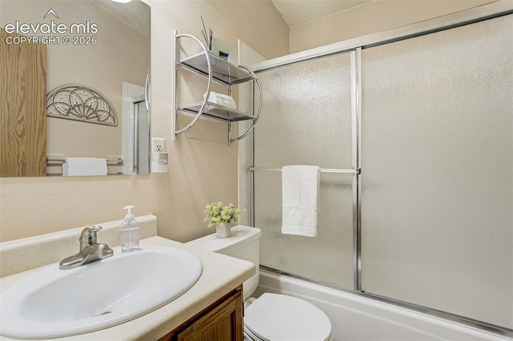 Image 24 of 50: Vanity with a white oval basin, brushed nickel faucet, and wood-finish cabi