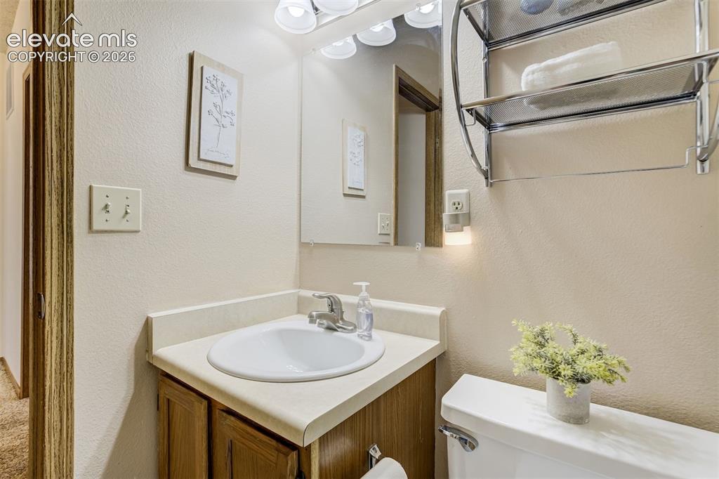 Image 25 of 50: Wood-finish vanity with an integrated sink and light-toned countertop, comp