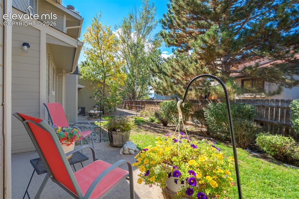 Image 3 of 50: Private patio with concrete surface, surrounded by lush landscaping and mat