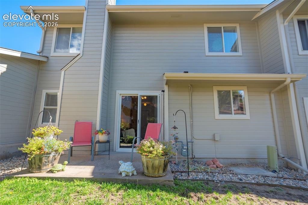 Image 30 of 50: Rear exterior featuring a concrete patio, sliding glass door, and multiple