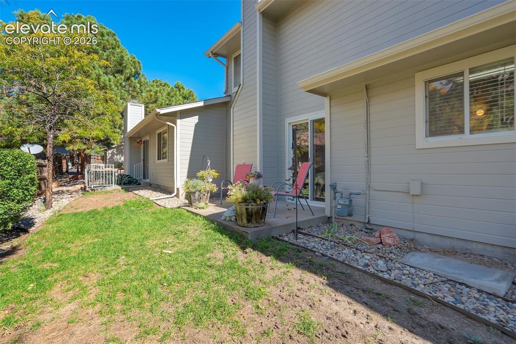 Image 31 of 50: Manicured lawn, concrete patio, sliding glass door, and exterior siding