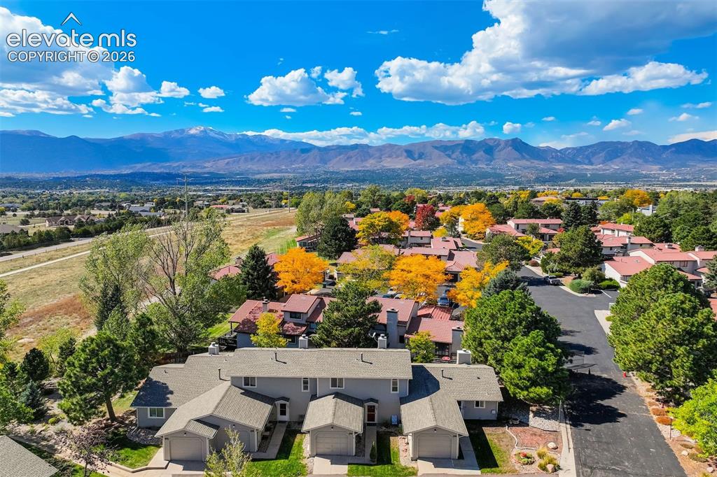 Image 34 of 50: Mountain range backdrop, residential neighborhood with mature trees, paved 