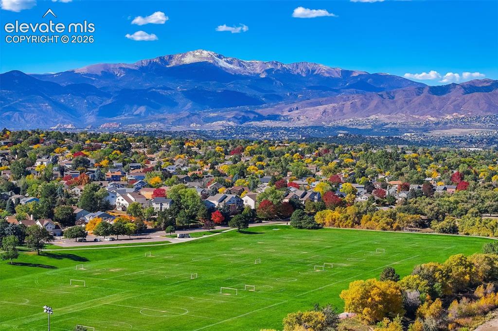 Image 39 of 50: Expansive green field with defined playing areas, surrounded by mature deci
