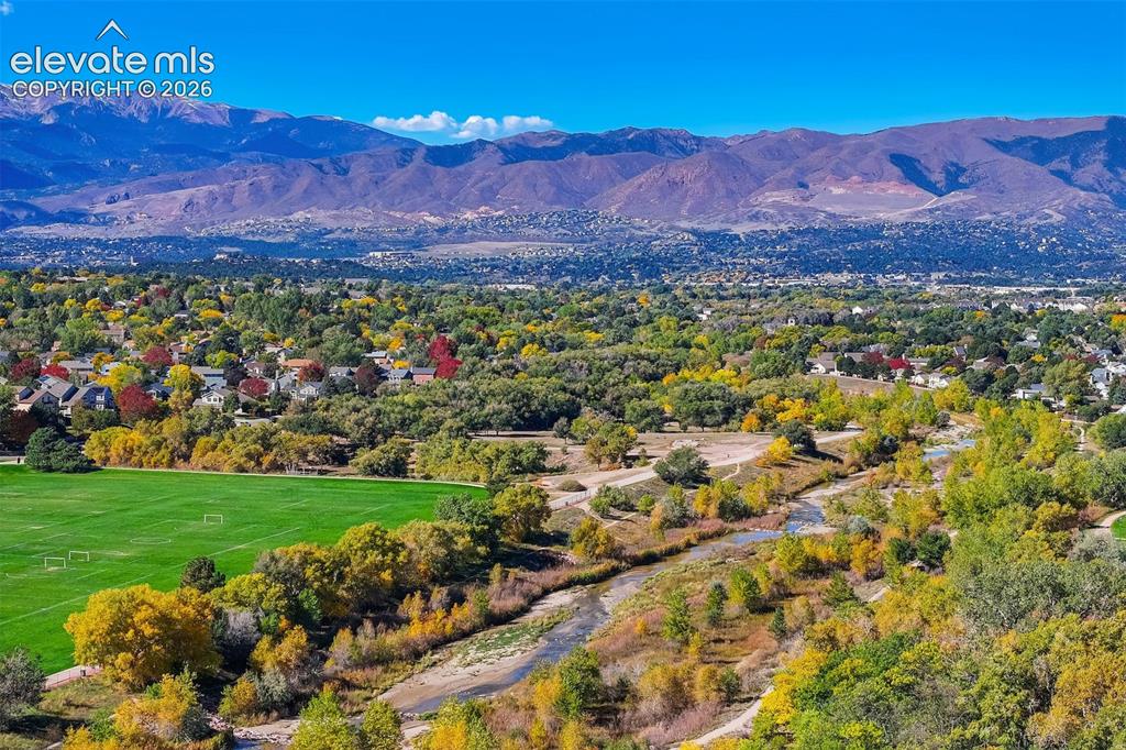 Image 40 of 50: Expansive landscape featuring distant mountains, a vibrant green field, a w