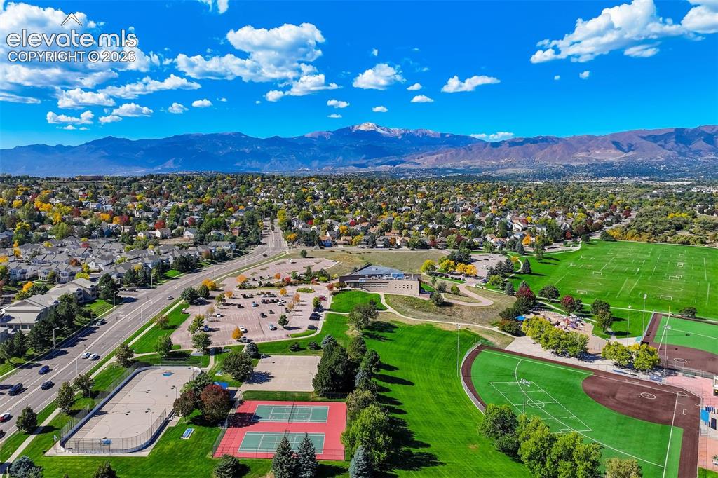 Image 46 of 50: Expansive neighborhood with mountain backdrop, featuring a large athletic f
