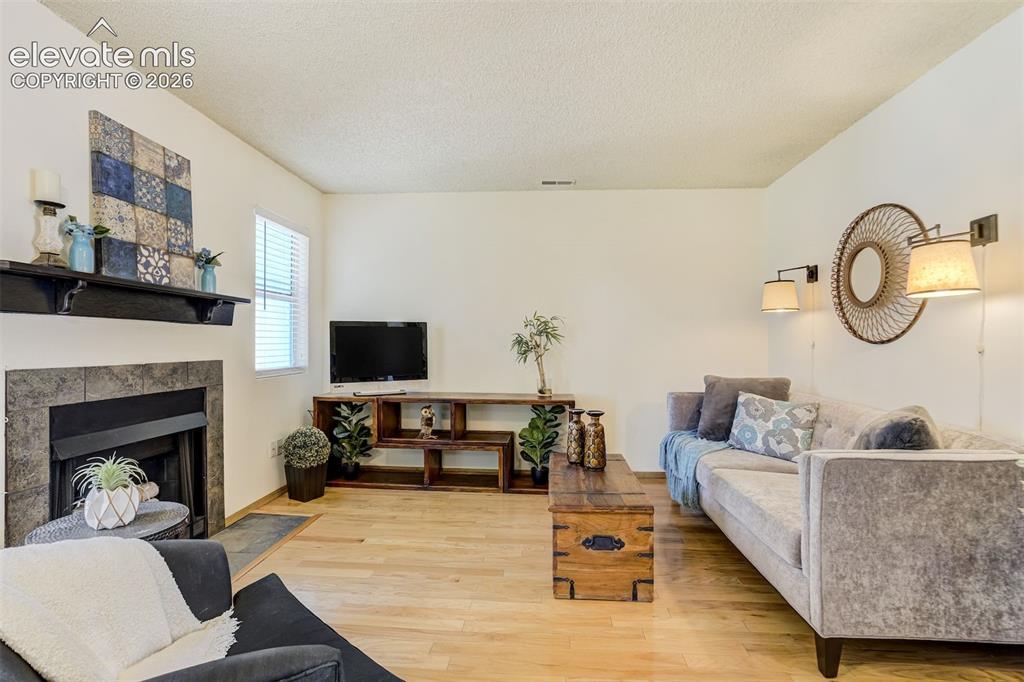 Image 5 of 50: Living space featuring wood-finish flooring, a stone-surround fireplace wit