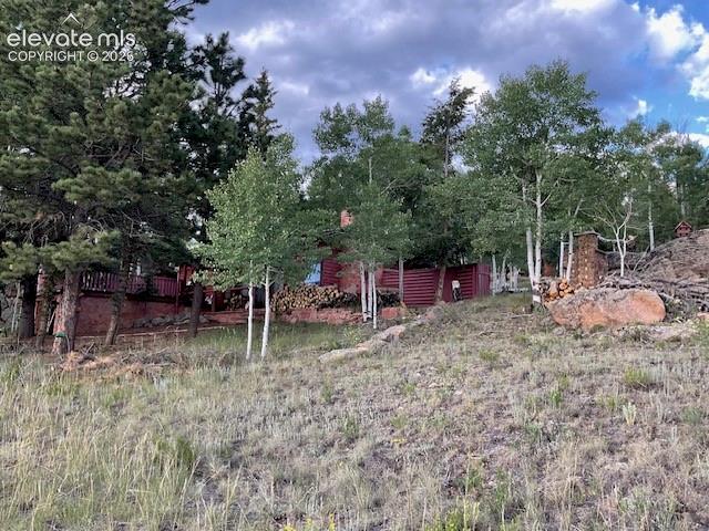 Image 13 of 36: Wood-sided exterior featuring a red finish, situated on a sloped lot with n