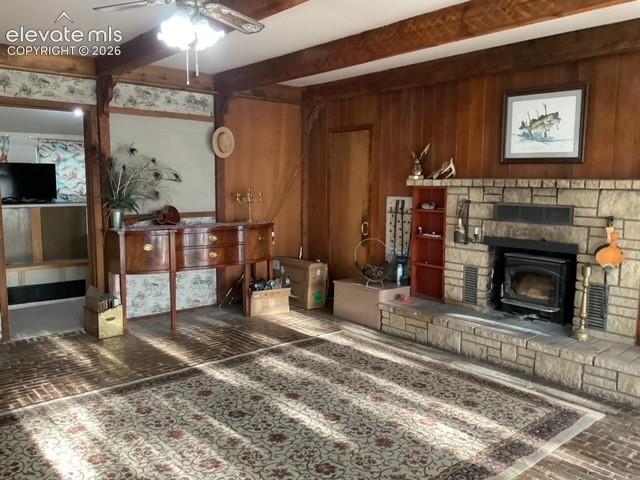 Image 20 of 36: Living area featuring wood paneling, exposed wood beams, and brick flooring