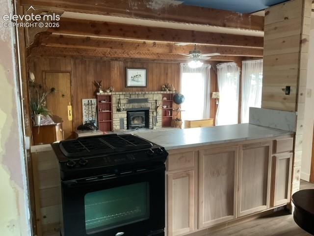 Image 30 of 36: Freestanding black range with natural wood-finish cabinetry and light-toned