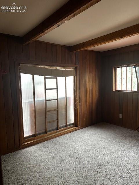 Image 32 of 36: Room featuring wood paneling, exposed wood ceiling beams, and a large windo