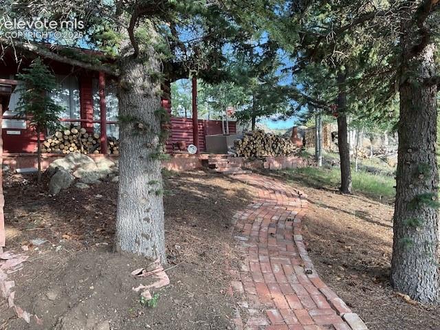 Image 4 of 36: Winding brick pathway leading to a red-sided structure with a covered front