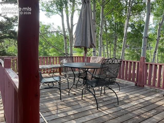 Image 5 of 36: Spacious wood deck with a red railing system, bordered by mature trees