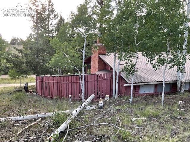 Image 8 of 36: Rustic cabin exterior featuring a red siding, a metal roof, and a red priva