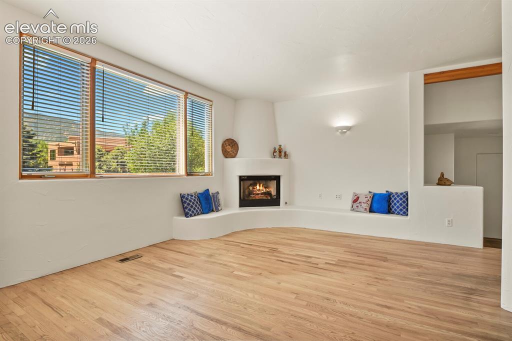 Image 6 of 39: hardwood floors & kiva fireplace with benches
