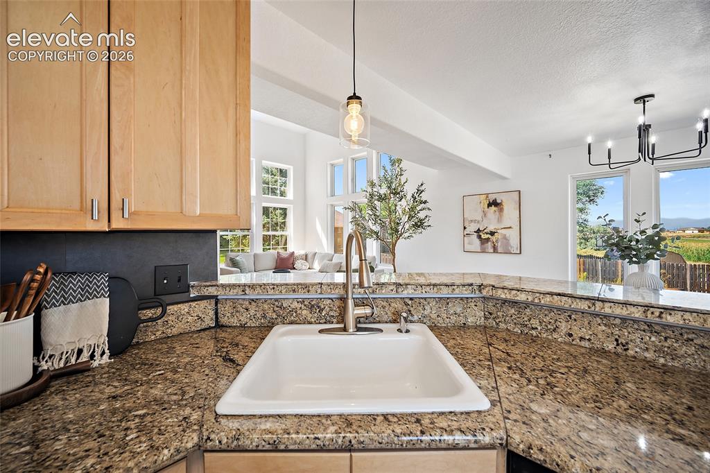 Image 11 of 40: Kitchen featuring a white undermount sink with a brass-finish faucet, grani