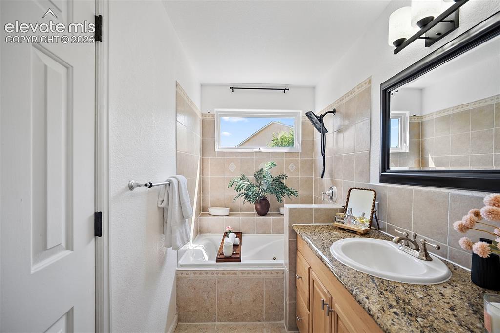 Image 15 of 40: Bathroom featuring a shower-tub combination with tile surround, a built-in 