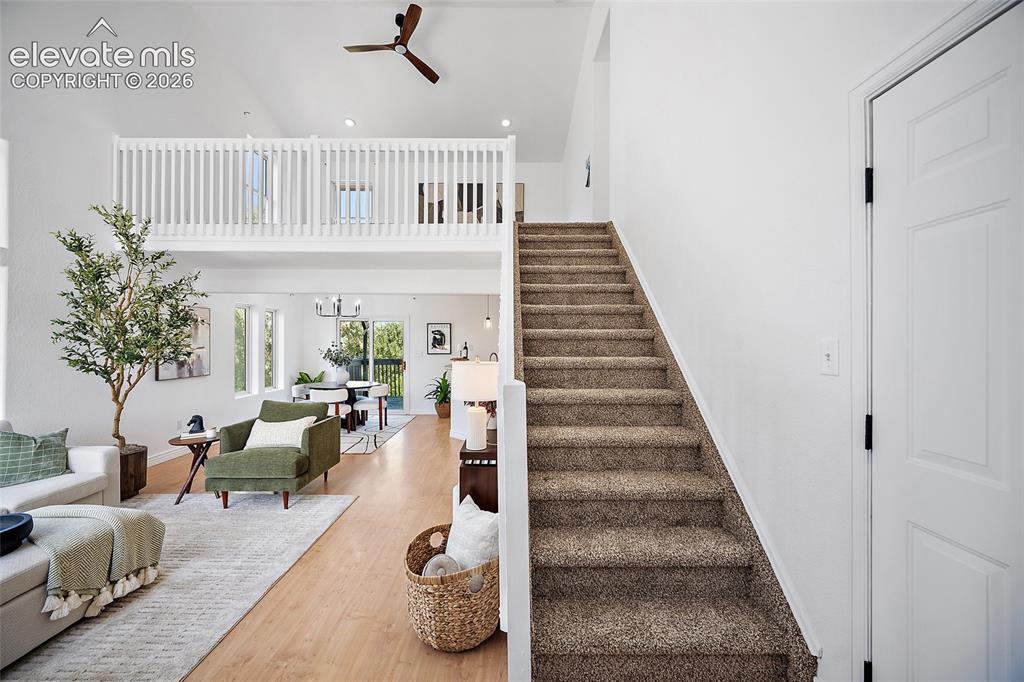 Image 16 of 40: Vaulted ceilings with a ceiling fan, a carpeted staircase, and wood-finish 