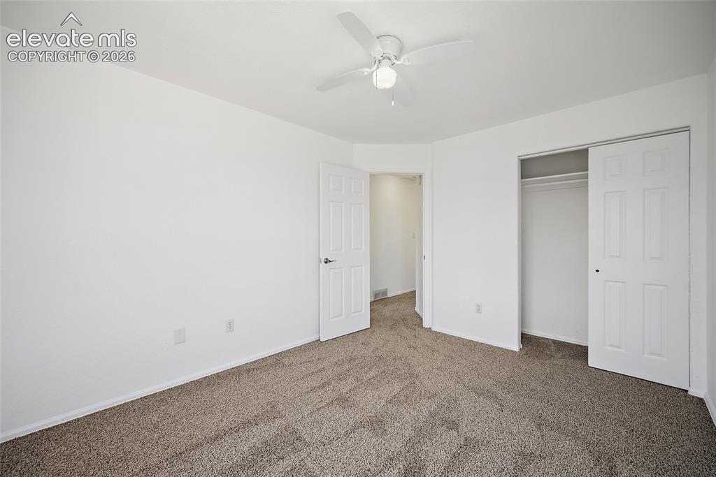 Image 19 of 40: Neutral-toned carpet flooring in a room featuring a ceiling fan with integr