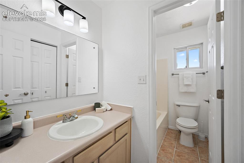 Image 21 of 40: Bathroom featuring a vanity with an integrated sink, a rectangular mirror, 