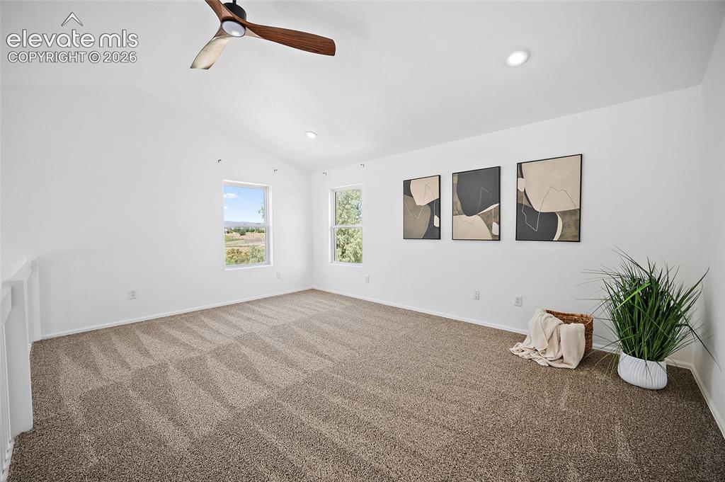 Image 23 of 40: Spacious room featuring vaulted ceilings, a wood-finish ceiling fan, recess