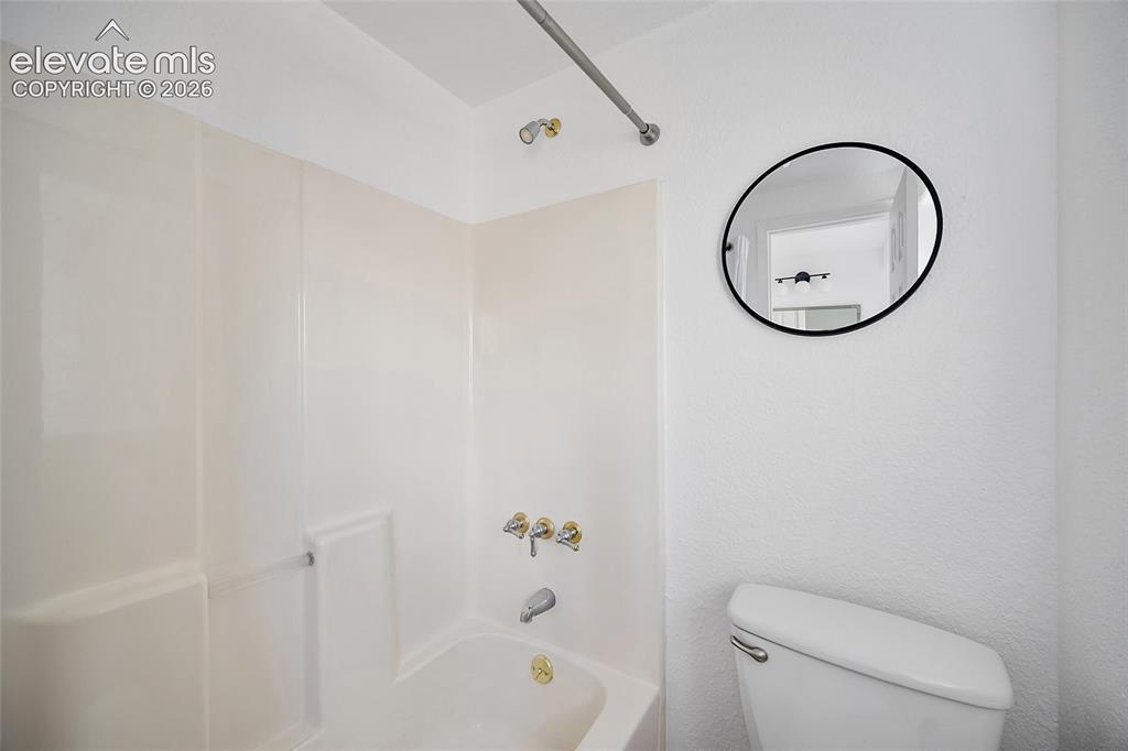 Image 26 of 40: Bathroom featuring a tub/shower combination with a shower rod, a wall-mount