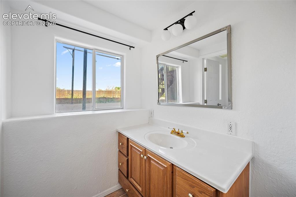 Image 27 of 40: Bathroom vanity with wood-finish cabinetry, a white countertop, and an inte