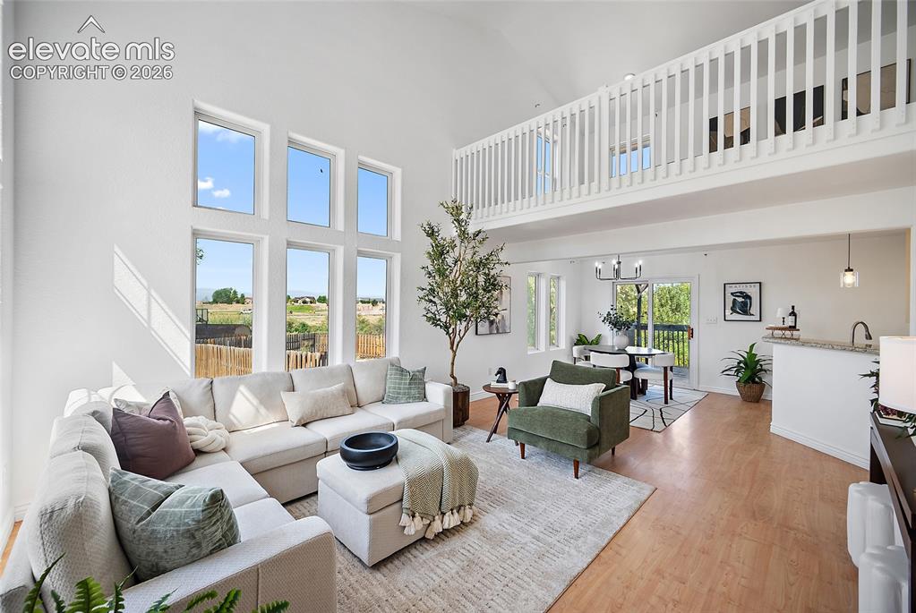 Image 3 of 40: Vaulted living room with a lofted walkway, large picture windows, wood-fini