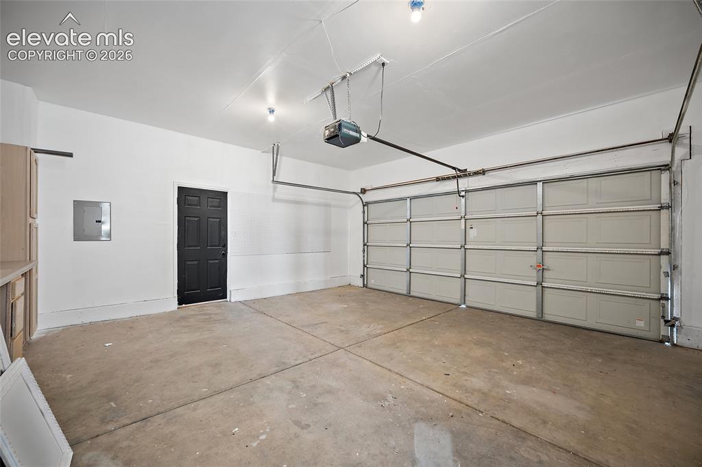 Image 35 of 40: Two-car garage with concrete flooring, a paneled overhead door, and a built